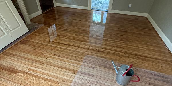A freshly polished wooden floor reflects light in an empty room.