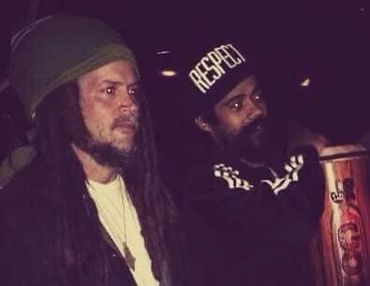 Two men in casual attire with serious expressions at night.