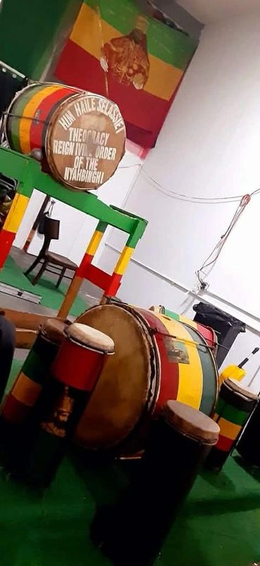 Drums and a drum with Rastafarian colors and a flag in the background.