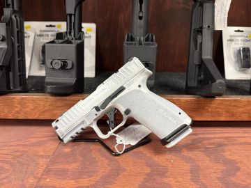 White semi-automatic handgun on wooden surface.