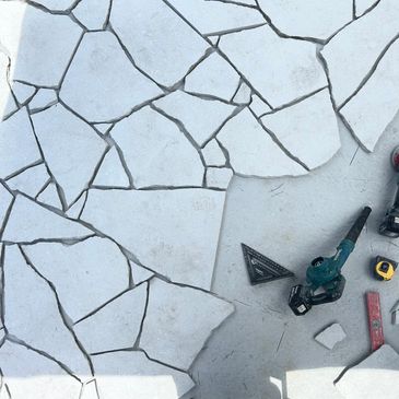 Tools and stones arranged for a stone paving project.