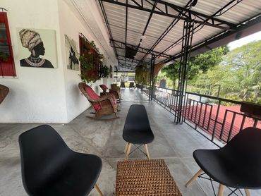 Spacious outdoor patio with black chairs, wicker rocking chairs, and vibrant wall art.