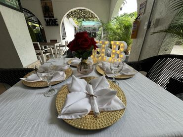 Elegant table setting with white napkins and red roses in a cozy outdoor dining area.