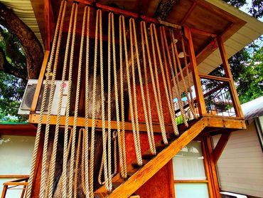 Wooden treehouse with rope railing and surrounding greenery.