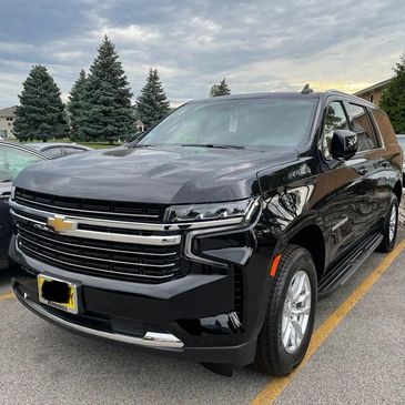 Black Chevrolet SUV parked under a cloudy sky in a parking lot.
