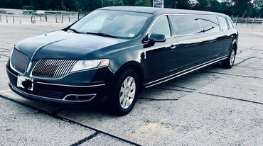 Black luxury stretch limousine parked in an outdoor lot.