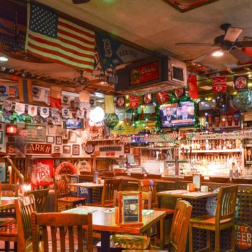 Cozy bar with wooden tables, chairs, and various flags and beers on display.