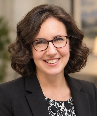 Smiling woman with glasses and curly hair.
