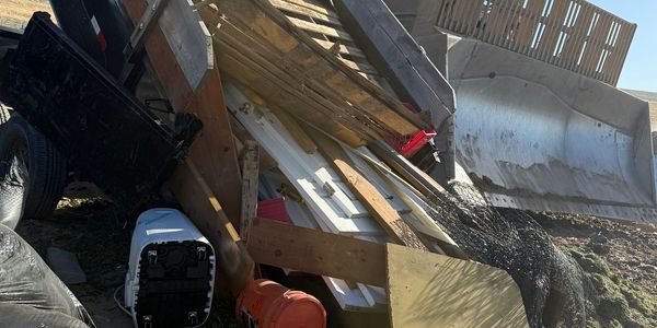 Pile of discarded wooden pallets and household items outdoors.