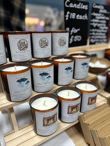 Hand-poured scented candles labeled with various calming themes displayed on wooden shelves.