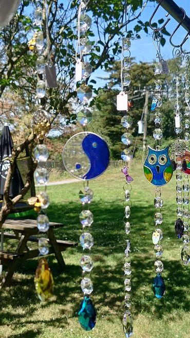Colorful crystal and stained glass sun catchers hanging outdoors.