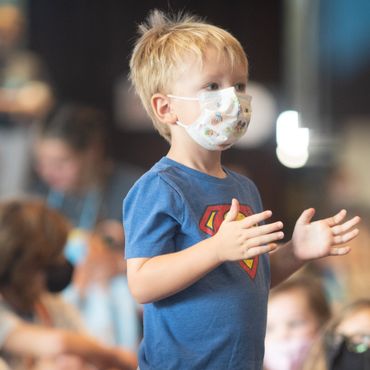 Boy, in mask, clapping.