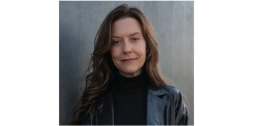 Woman with long brown hair wearing a black leather jacket and turtleneck.
