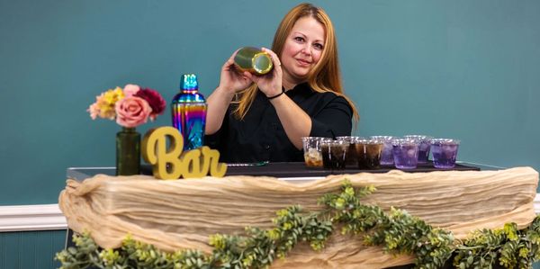 Bartender shaking a cocktail behind a decorated bar counter.