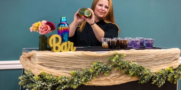 Bartender shaking a cocktail behind a decorated bar counter.