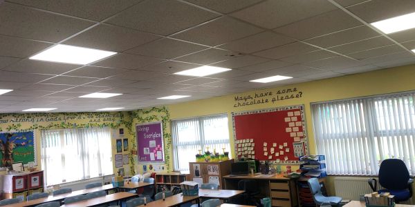 A bright classroom with desks, chairs, and educational displays on the walls.