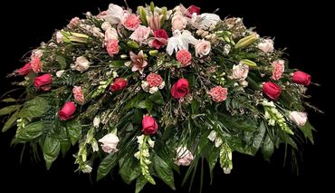Elegant floral arrangement with pink and red roses, lilies, and lush greenery.