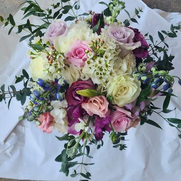 A colorful bouquet of mixed flowers with greenery on white paper.