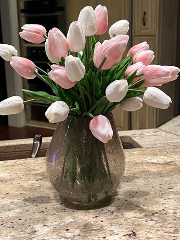A bouquet of pink and white tulips in a vase on a kitchen counter.