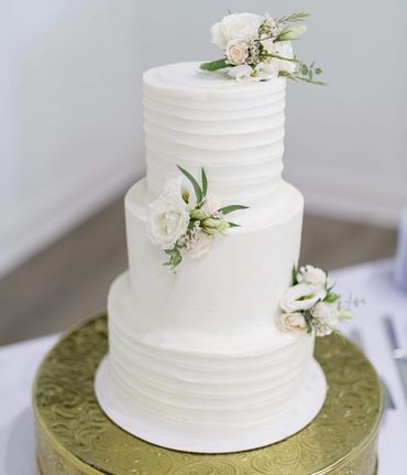 Elegant three-tier white wedding cake adorned with delicate white flowers.