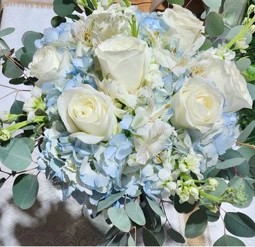 Elegant bouquet of white roses and blue hydrangeas with eucalyptus leaves.