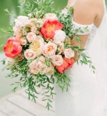Bride holding a vibrant bouquet of mixed flowers with greenery.