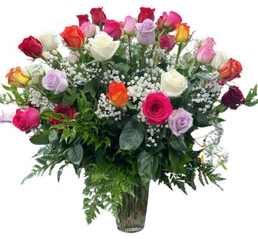 Colorful rose bouquet with white filler flowers in a clear vase.