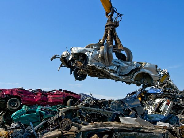 Crane lifting a car into a car graveyard
