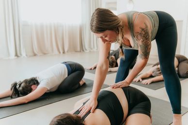 Yoga instructor assisting student in a yoga class.