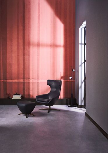 Zwart ledere Caruzzo fauteuil met poef Forte in een mooi interieur met betonvloer