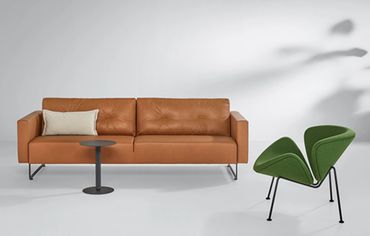 Rechte strakke Mare bank van Artifort in cognac leder en een Orange slice fauteuil in een groene sto