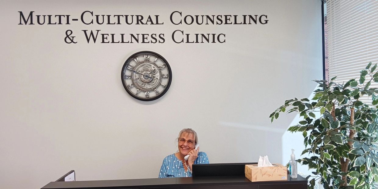 Receptionist smiling at the Multi-Cultural Counseling & Wellness Clinic front desk.