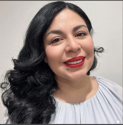 Smiling woman with long black hair and red lipstick.