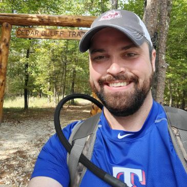 Man smiling on a forest trail.