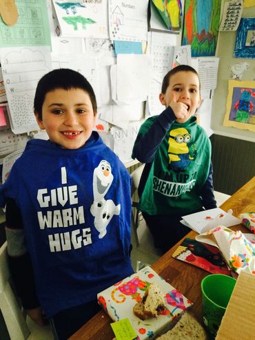 Two boys smiling joyfully with fun graphic tees and snacks at a table.