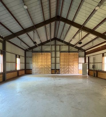 Empty spacious metal and wood barn interior with concrete floor.