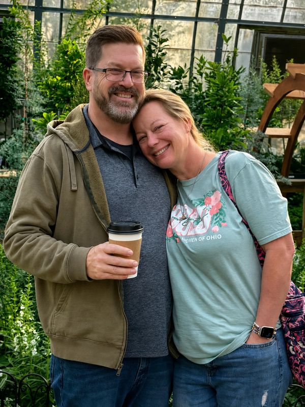 Smiling couple enjoying a moment outdoors with coffee.