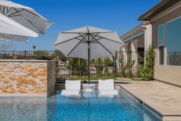 Poolside umbrellas and lounge chairs under a clear sky.