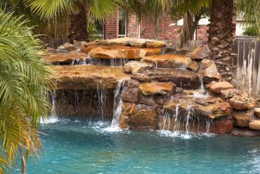 Backyard waterfall flowing into a pool.