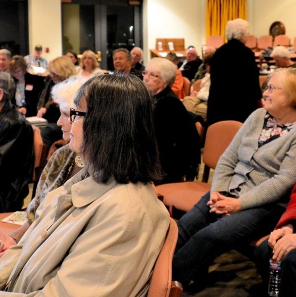 A group of elderly people seated attentively in a community event.