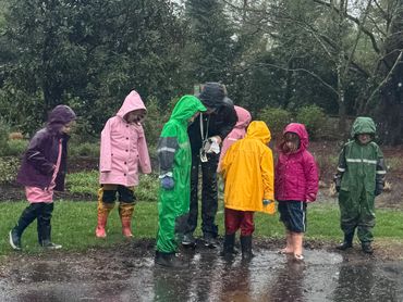 Children in colorful raincoats playing in a puddle on a rainy day.