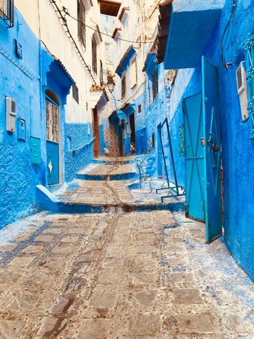 Narrow street with vibrant blue walls and cobblestone path.