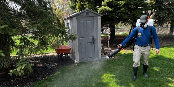 Licensed BuzzSkito specialist treating wooded perimeter for ticks at a Burlington home