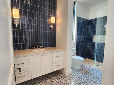 Modern bathroom with blue tiles and patterned floor.