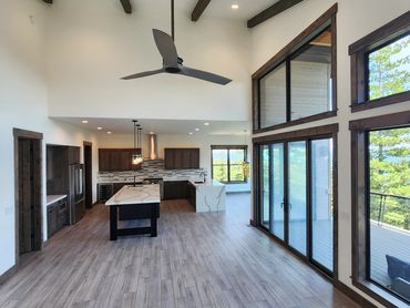 Modern open-concept kitchen and living area with large windows and wood accents.
