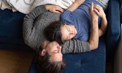 Couple lying on a blue couch, embracing peacefully.