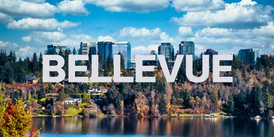 View of Bellevue city skyline with lake and autumn trees under a blue sky.