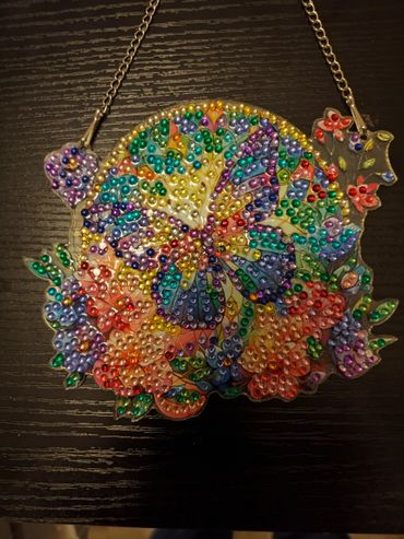 Colorful beaded butterfly and flower necklace on dark wood.