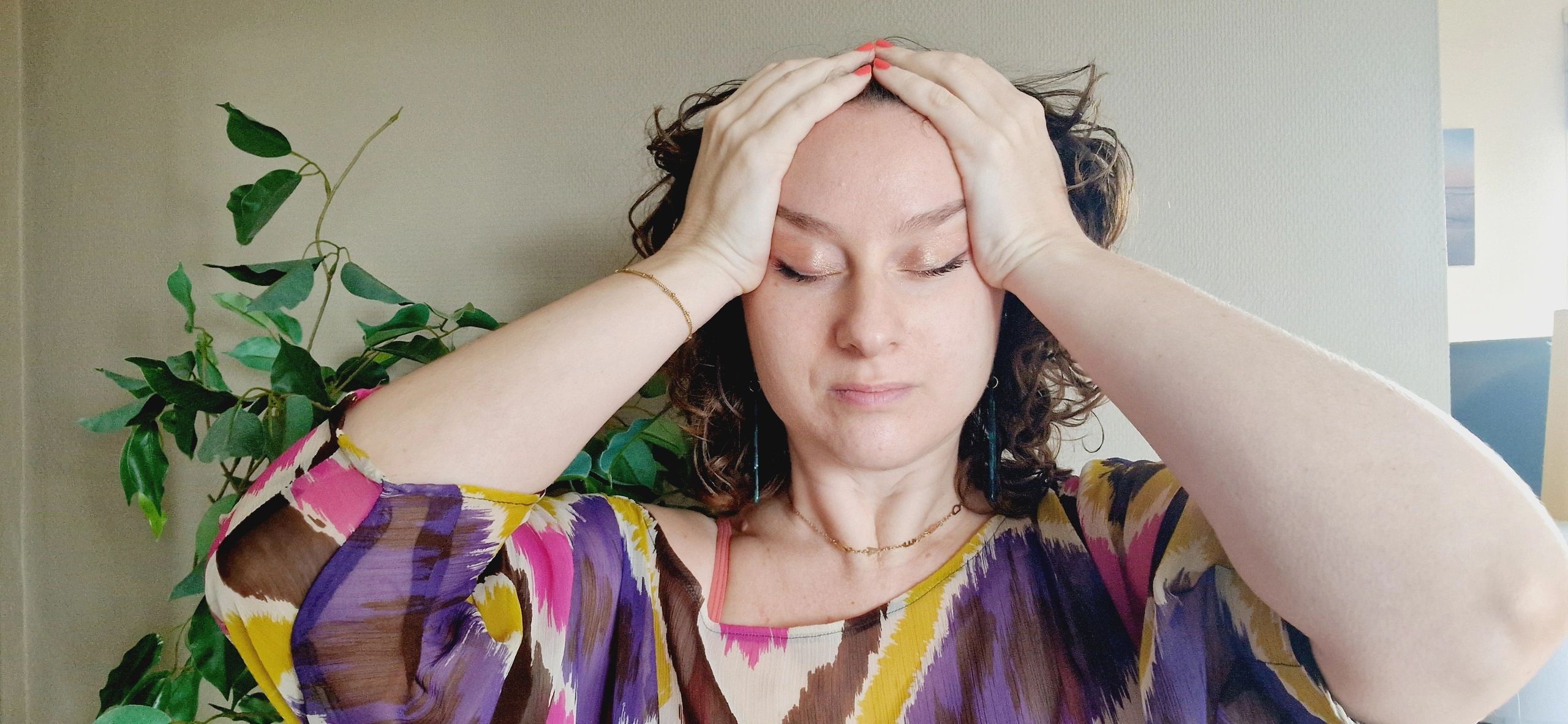 Woman with closed eyes holding her head, appearing stressed or tired.