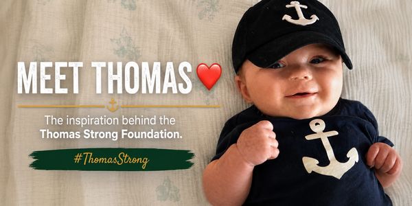Baby Thomas with a smiling face and anchor-themed outfit.